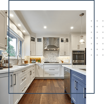 A kitchen with white cabinets and wood floors.