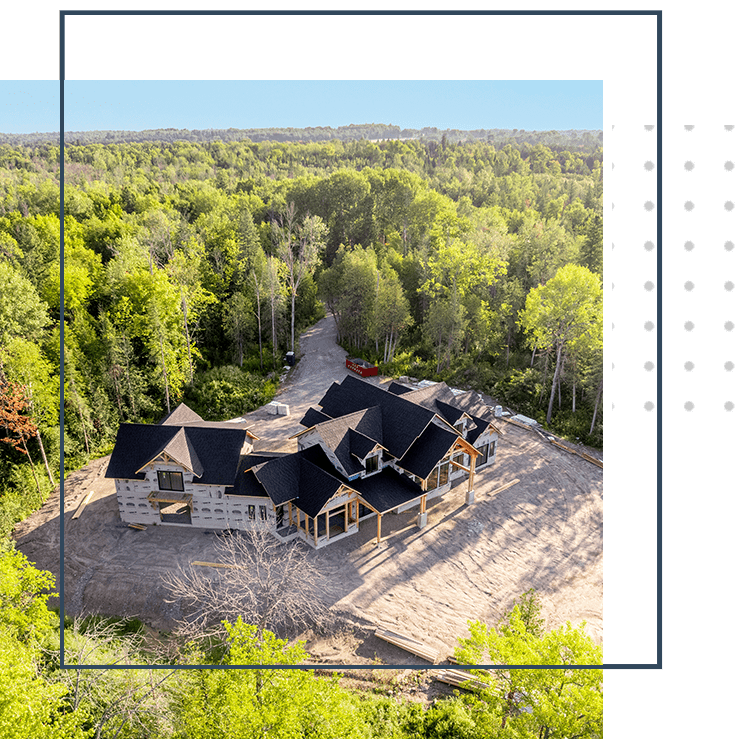A aerial view of a custom home in the middle of a forest.